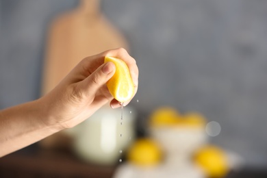 Photo of Young woman squeezing lemon on blurred background