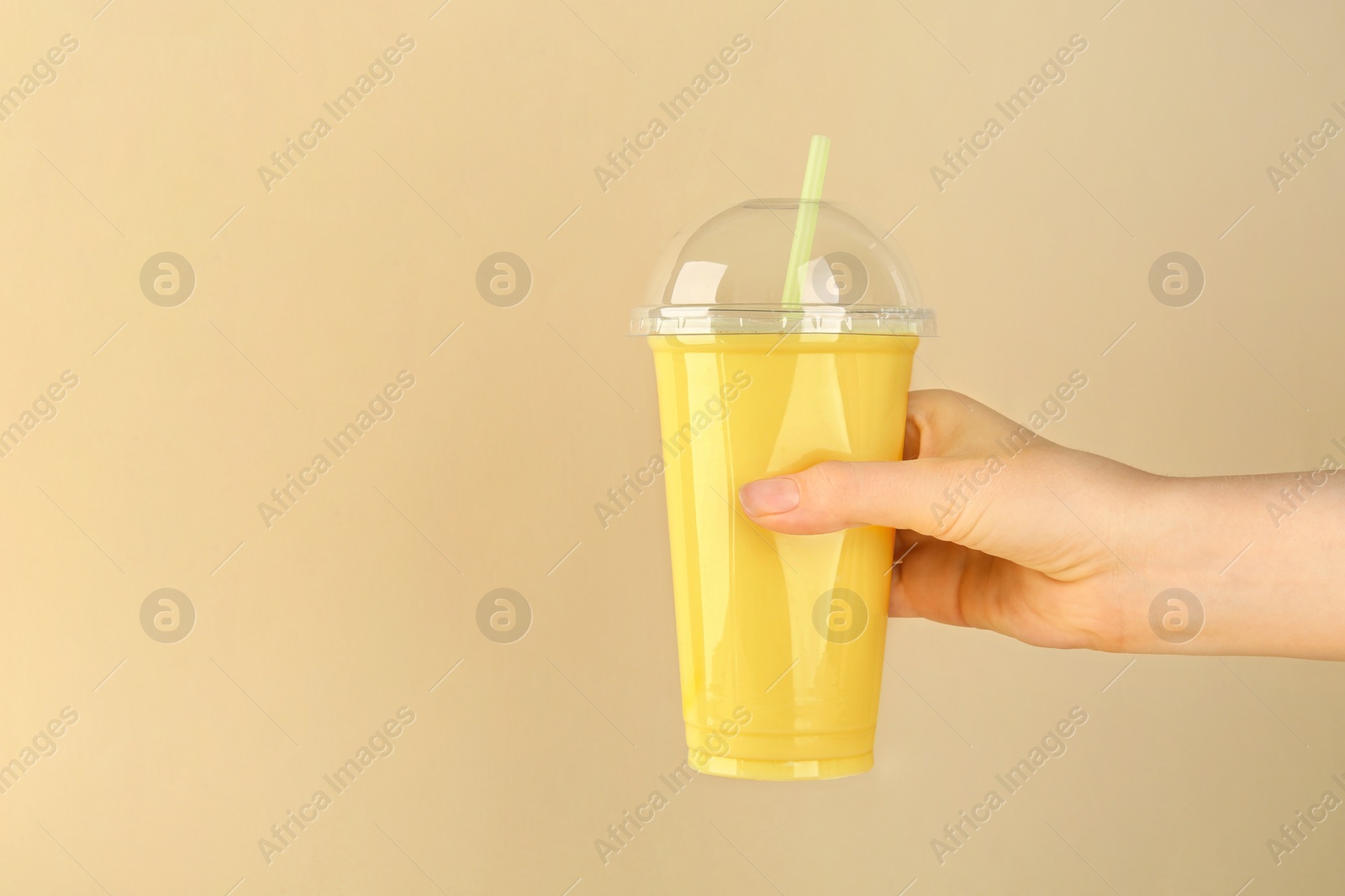 Photo of Woman with plastic cup of tasty smoothie on beige background, closeup. Space for text