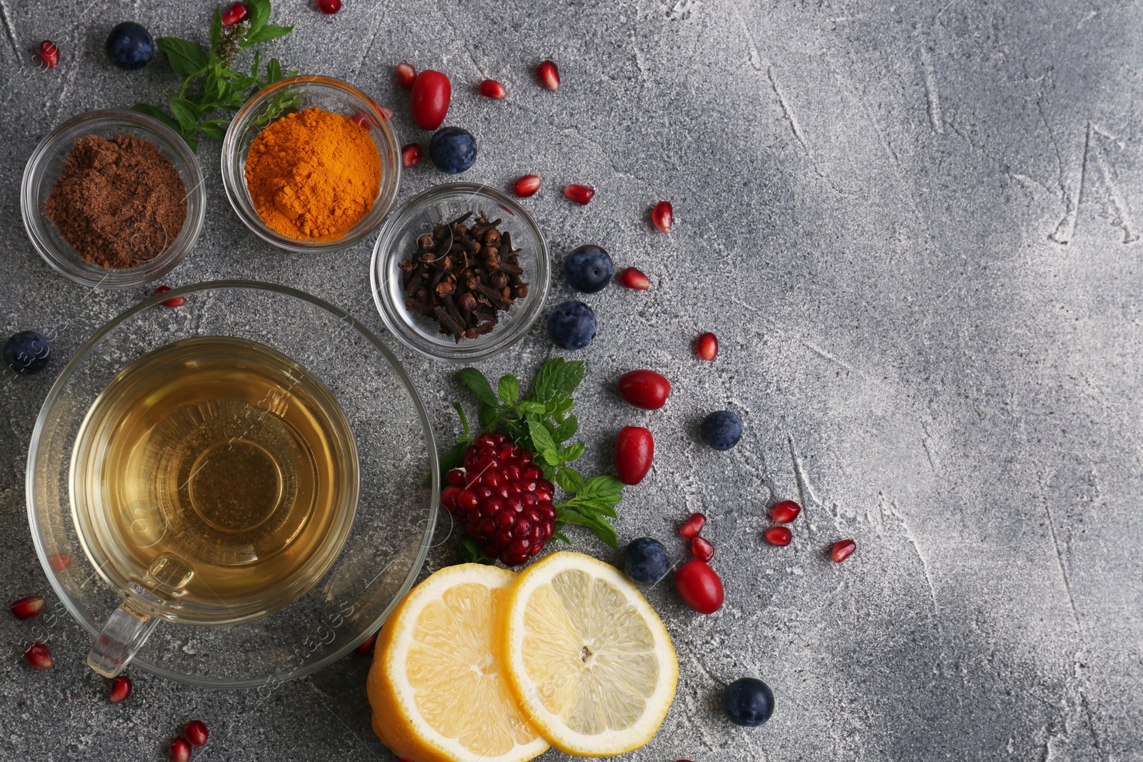 Photo of Cup with delicious immunity boosting tea and ingredients on grey table, flat lay. Space for text