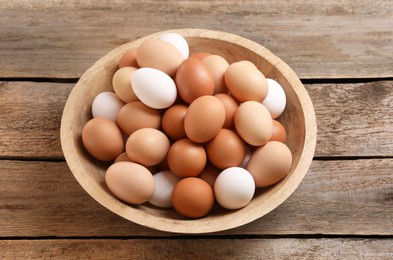 Photo of Chicken eggs in bowl on wooden table