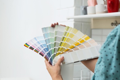 Photo of Female interior designer with color palette samples indoors, closeup