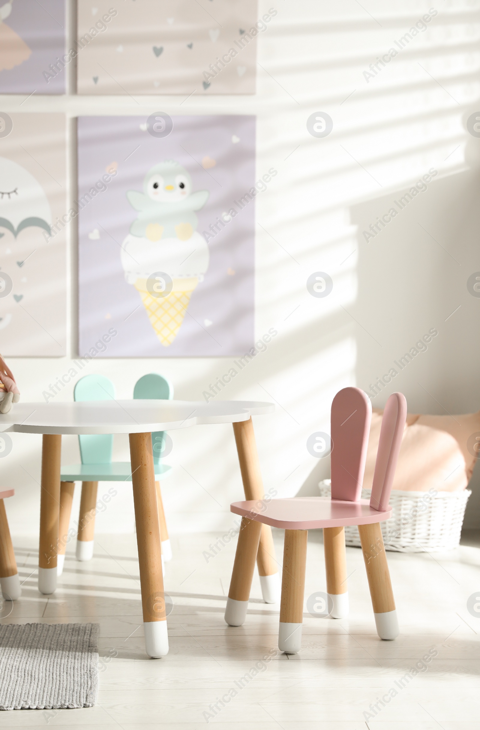 Photo of Small table and chairs with bunny ears in children's room interior