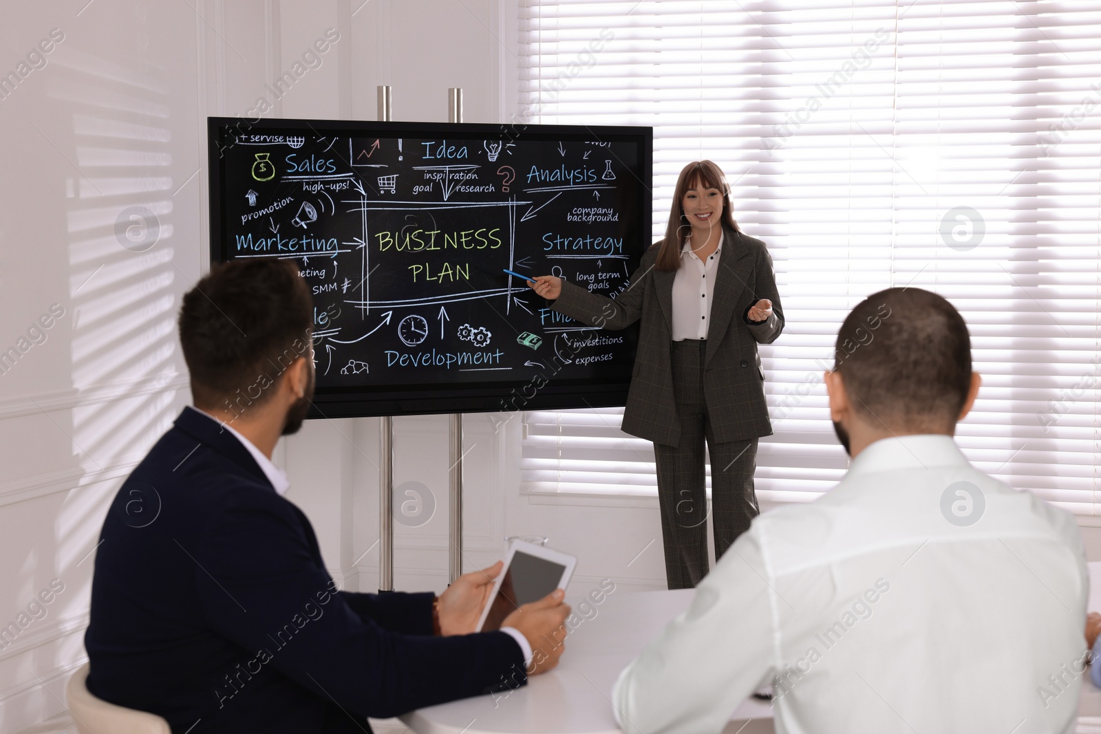 Photo of Business trainer using interactive board in meeting room during presentation