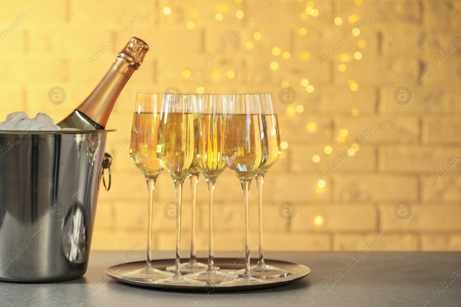 Photo of Glasses of champagne and ice bucket with bottle on grey table