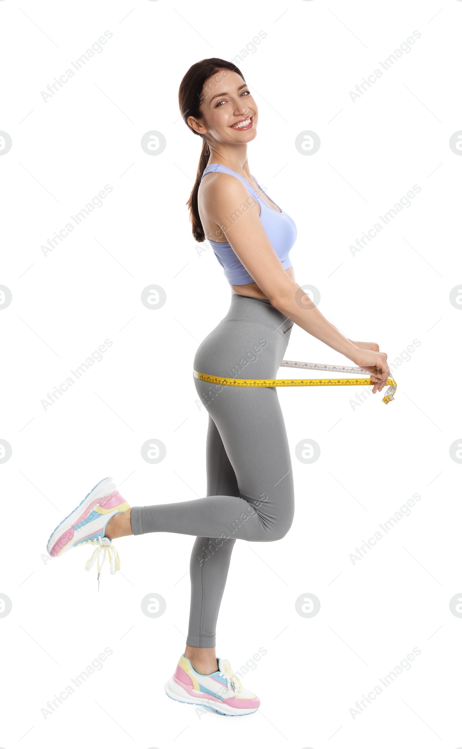 Photo of Happy young woman with measuring tape showing her slim body against white background