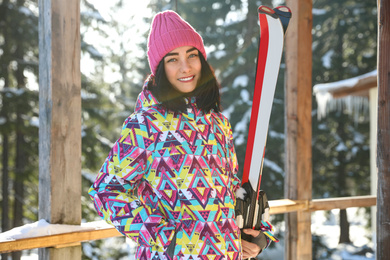 Photo of Young woman with ski wearing winter sport clothes in forest