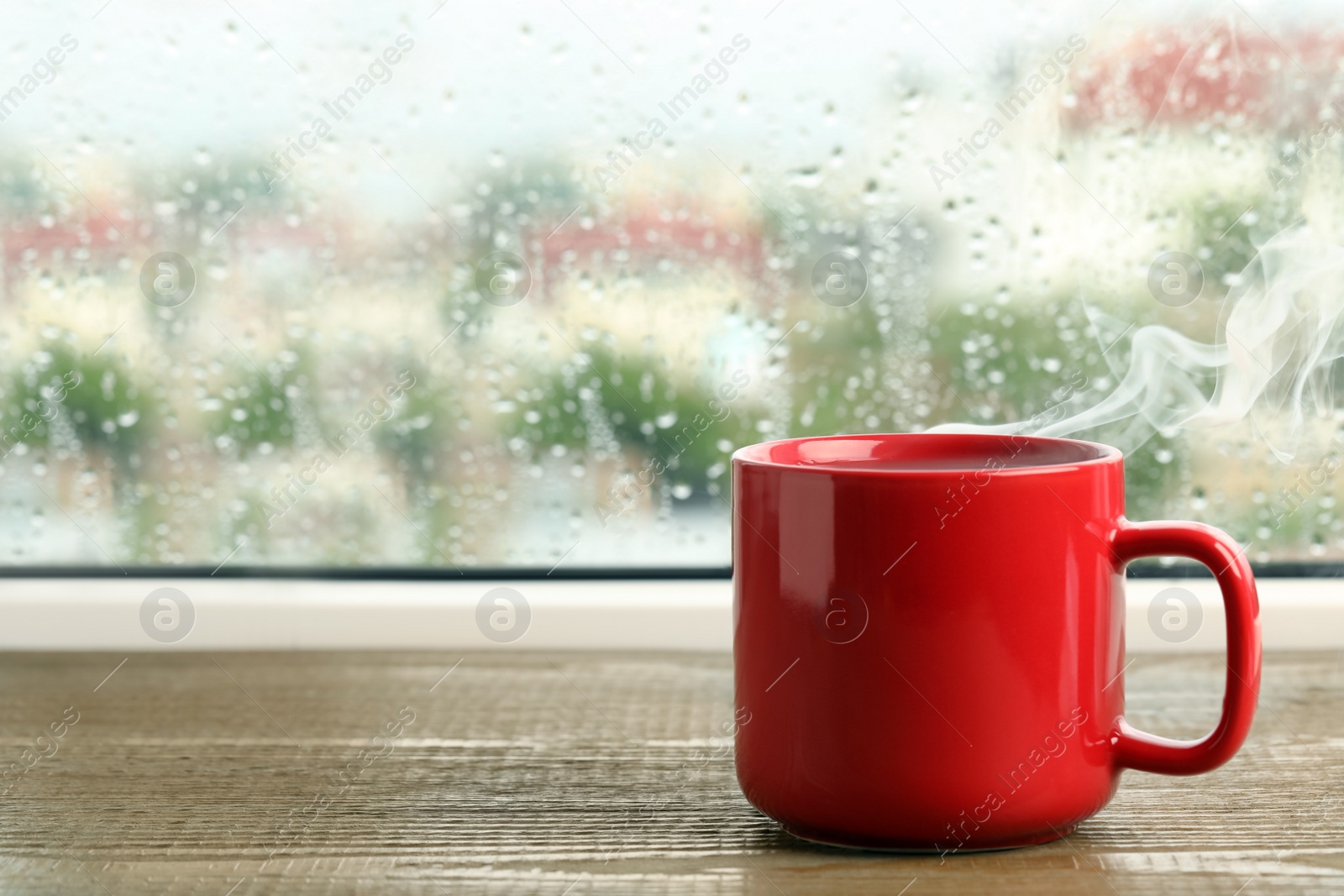 Photo of Cup of hot drink near window on rainy day. Space for text