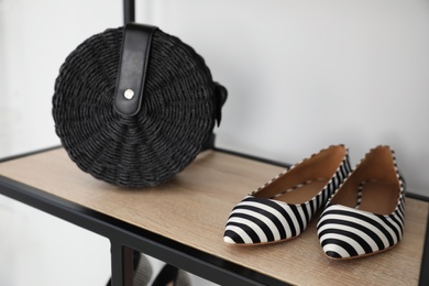 Photo of Stylish shoes and bag on shelf indoors