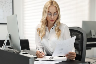 Secretary working with document at table in office