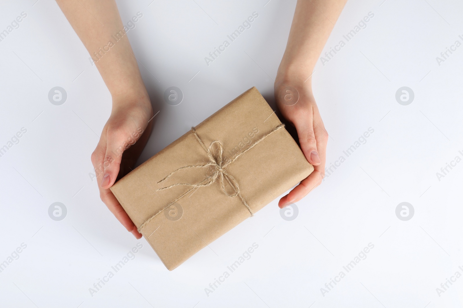 Photo of Woman holding parcel wrapped in kraft paper on white background, top view