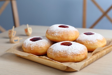 Photo of Hanukkah doughnuts with jelly and sugar powder served on wooden table, closeup