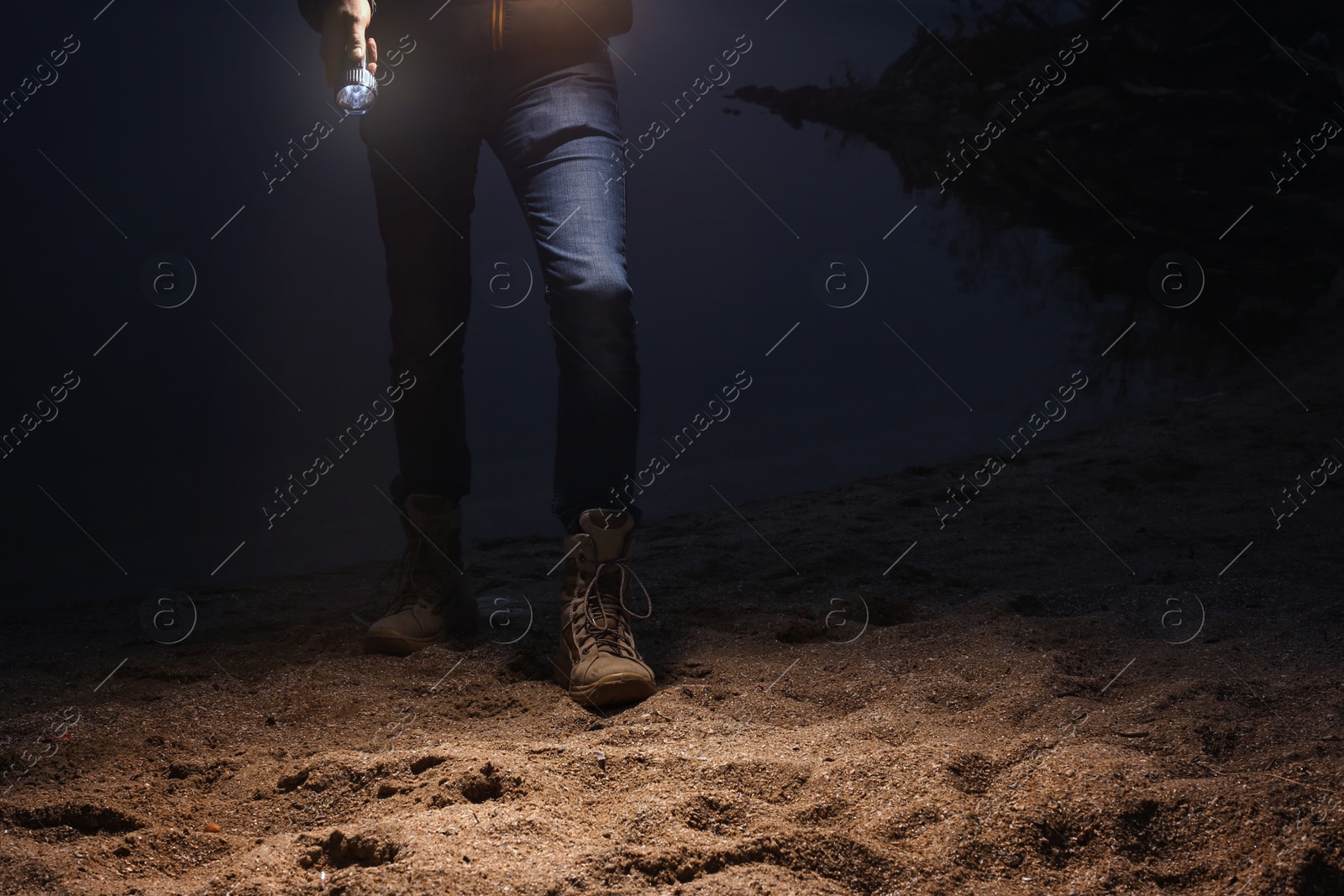 Photo of Man with flashlight walking at riverside, closeup