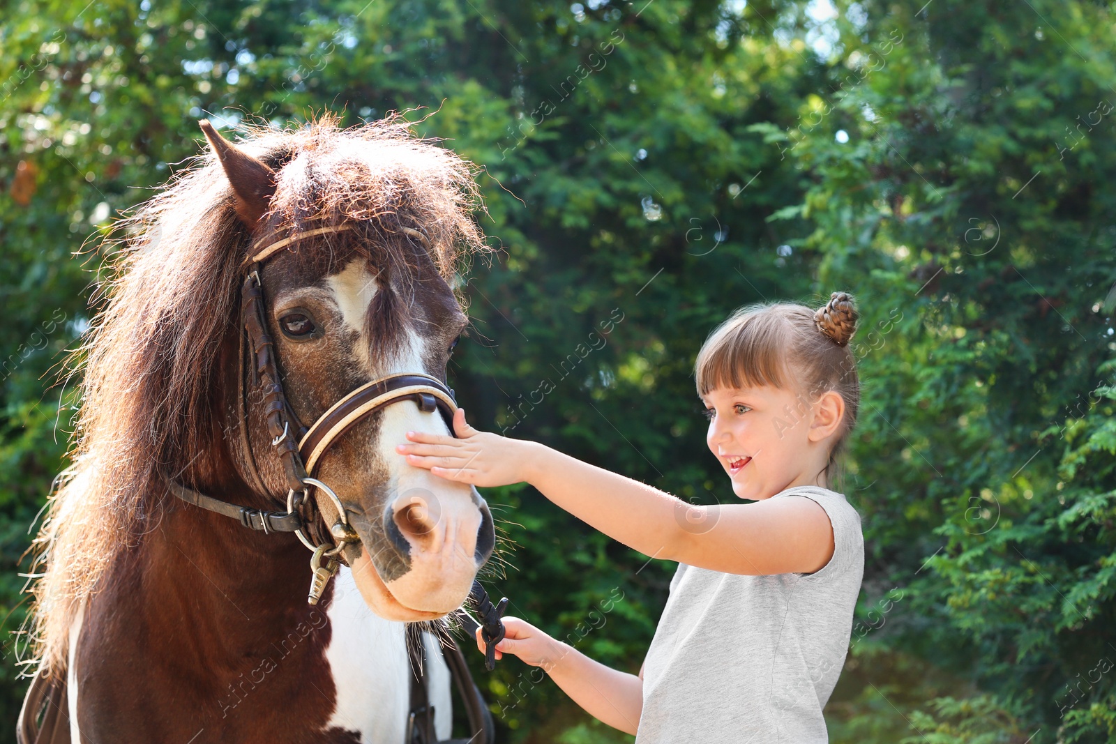 Photo of Cute little girl with her pony in green park