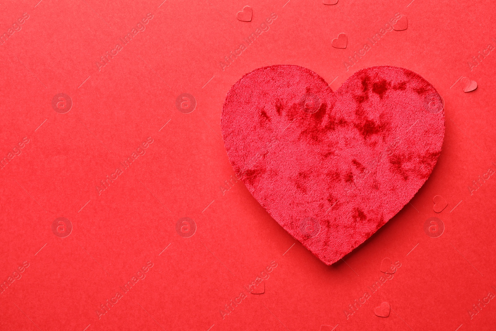 Photo of One velvet heart on red background, top view. Space for text