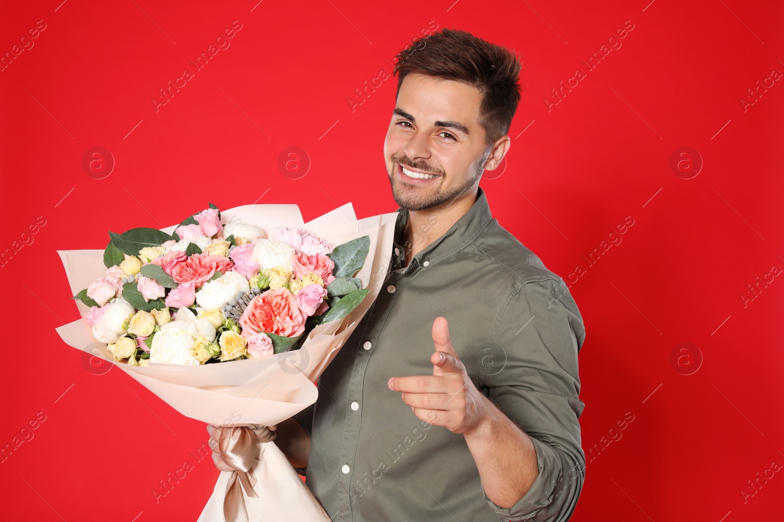 Photo of Young handsome man with beautiful flower bouquet on red background