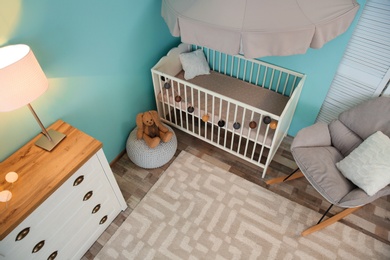 Photo of Modern interior of light cozy baby room with crib, view from above