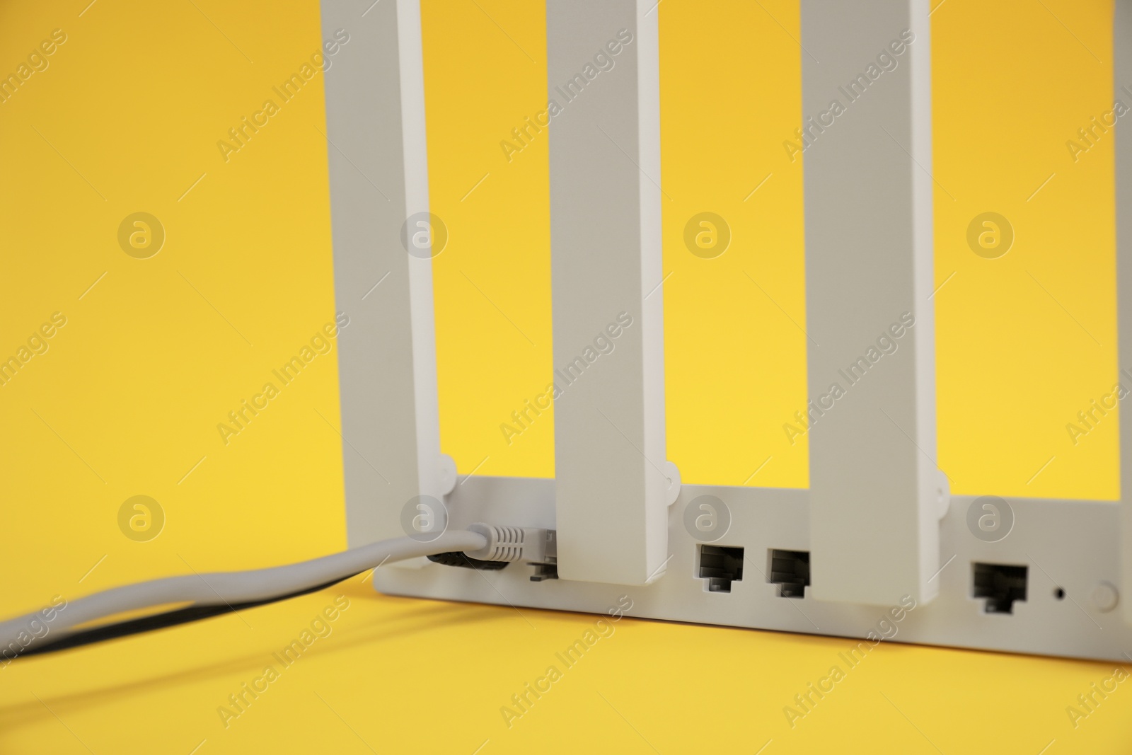 Photo of Modern Wi-Fi router on yellow background, closeup