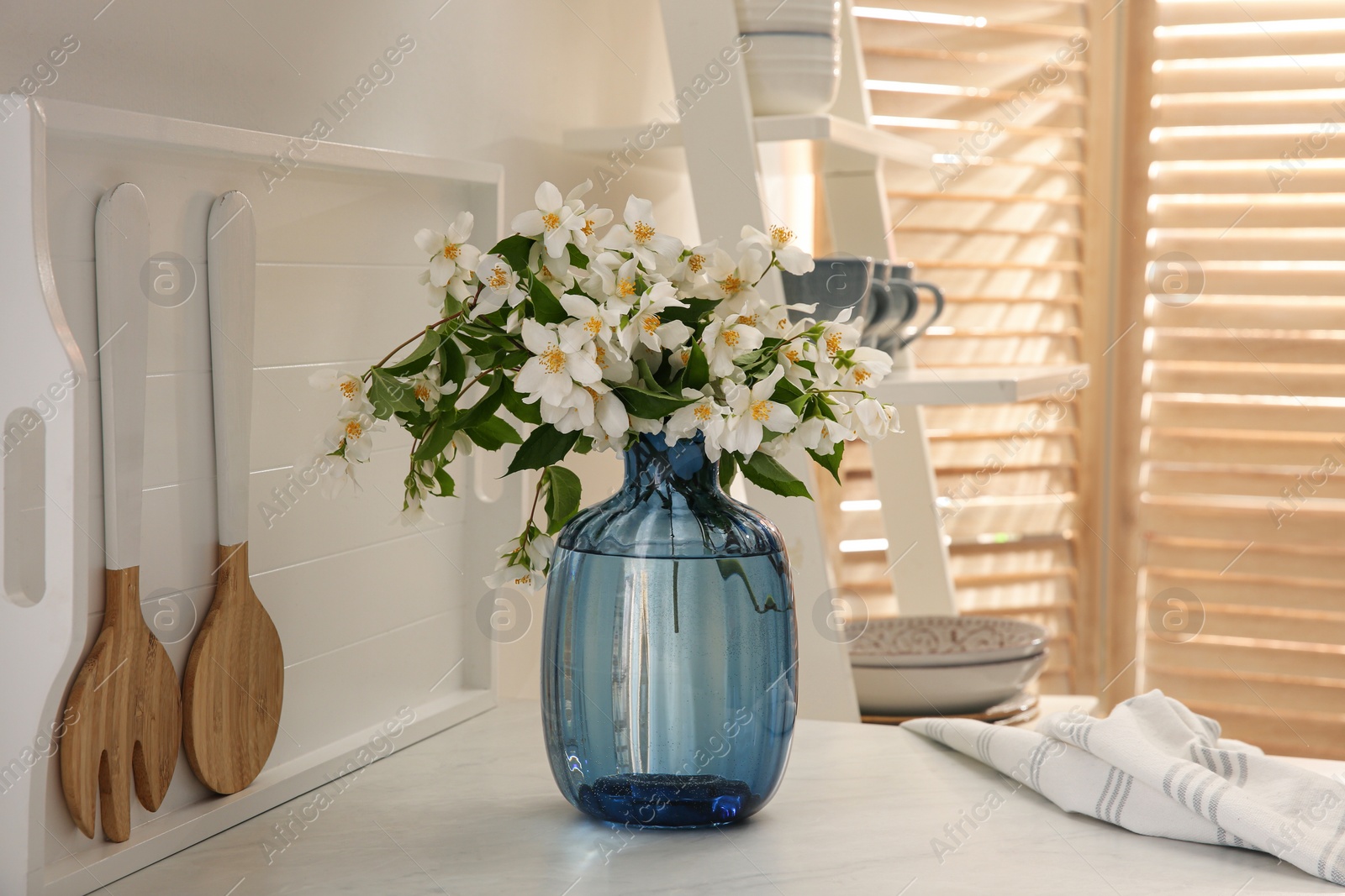 Photo of Bouquet of beautiful jasmine flowers on countertop in kitchen