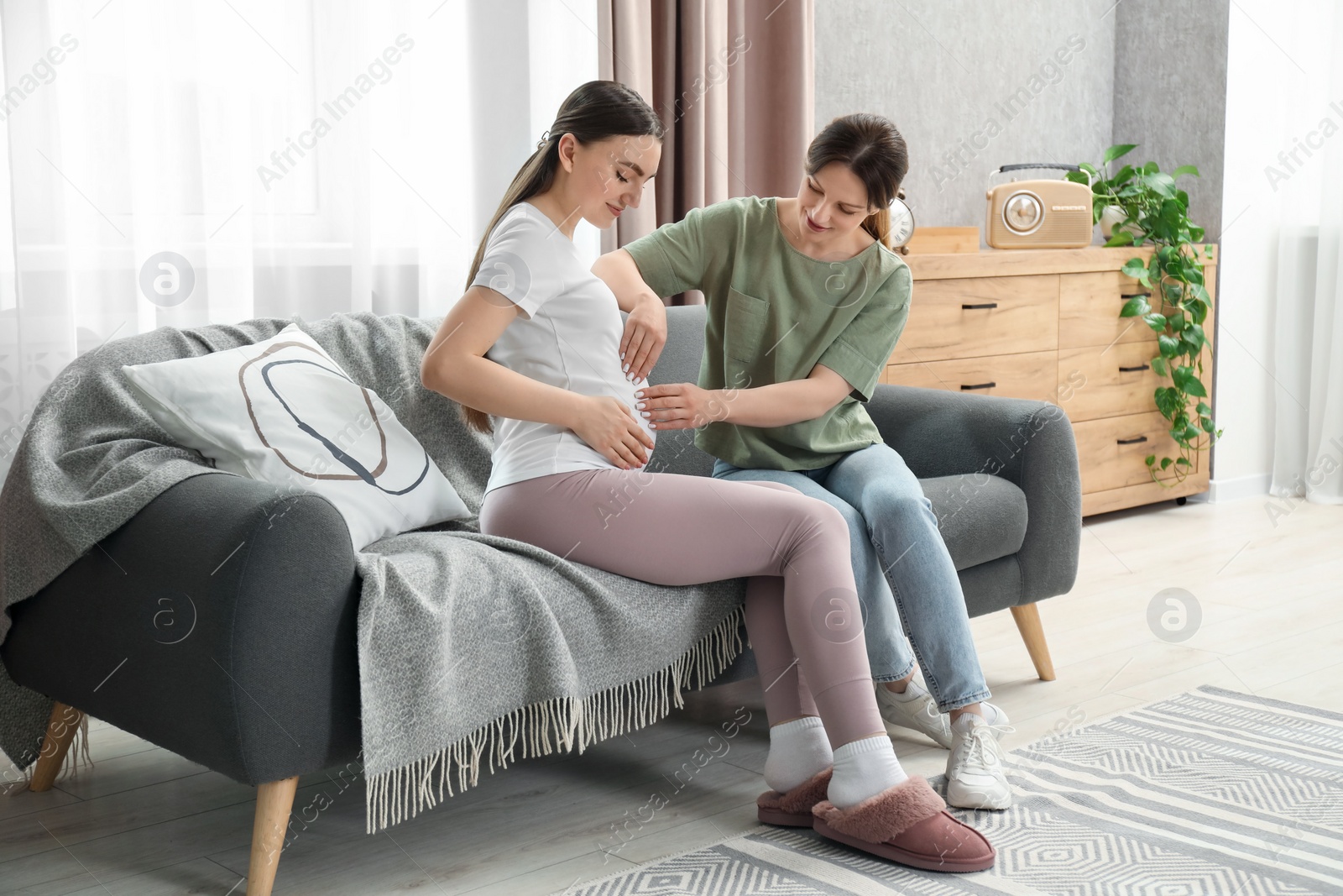 Photo of Doula taking care of pregnant woman on sofa at home. Preparation for child birth