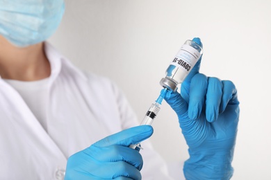 Photo of Doctor filling syringe with vaccine against Covid-19 on white background, closeup