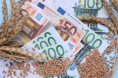 Import and export concept. Ears of wheat and banknotes on light blue background, flat lay