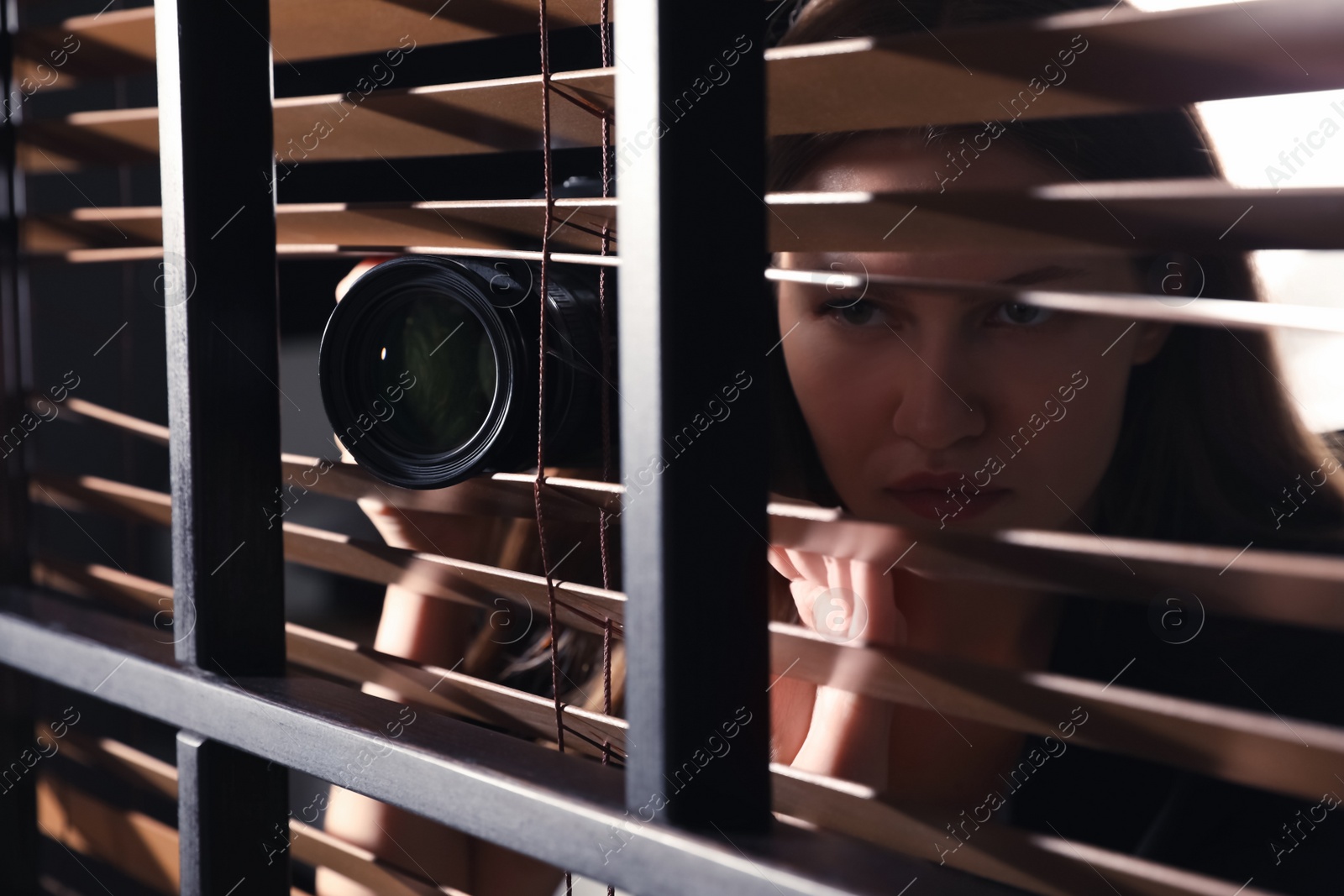 Photo of Private detective with camera spying near window indoors, closeup