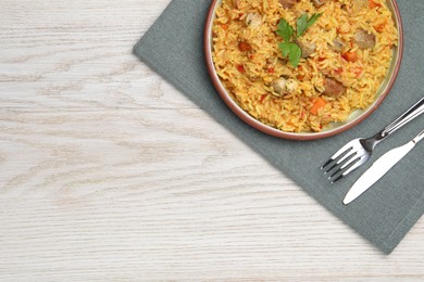 Photo of Delicious pilaf with meat served on white wooden table, top view. Space for text
