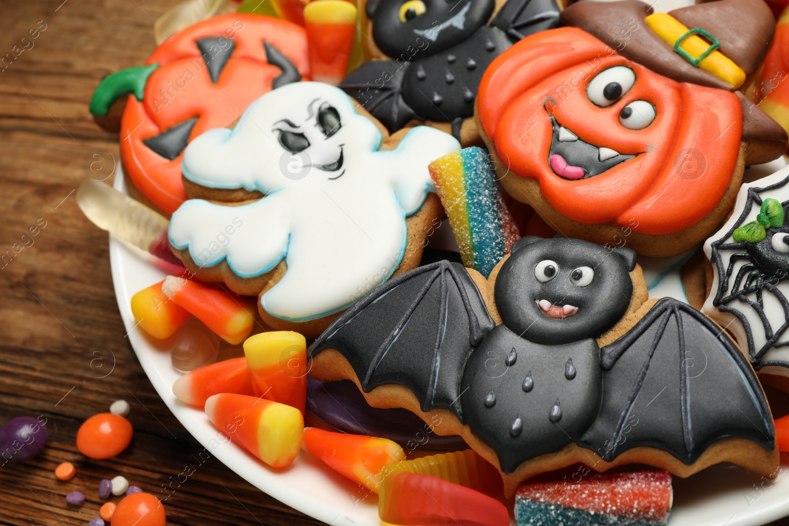 Photo of Tasty cookies and sweets for Halloween party on wooden table, closeup