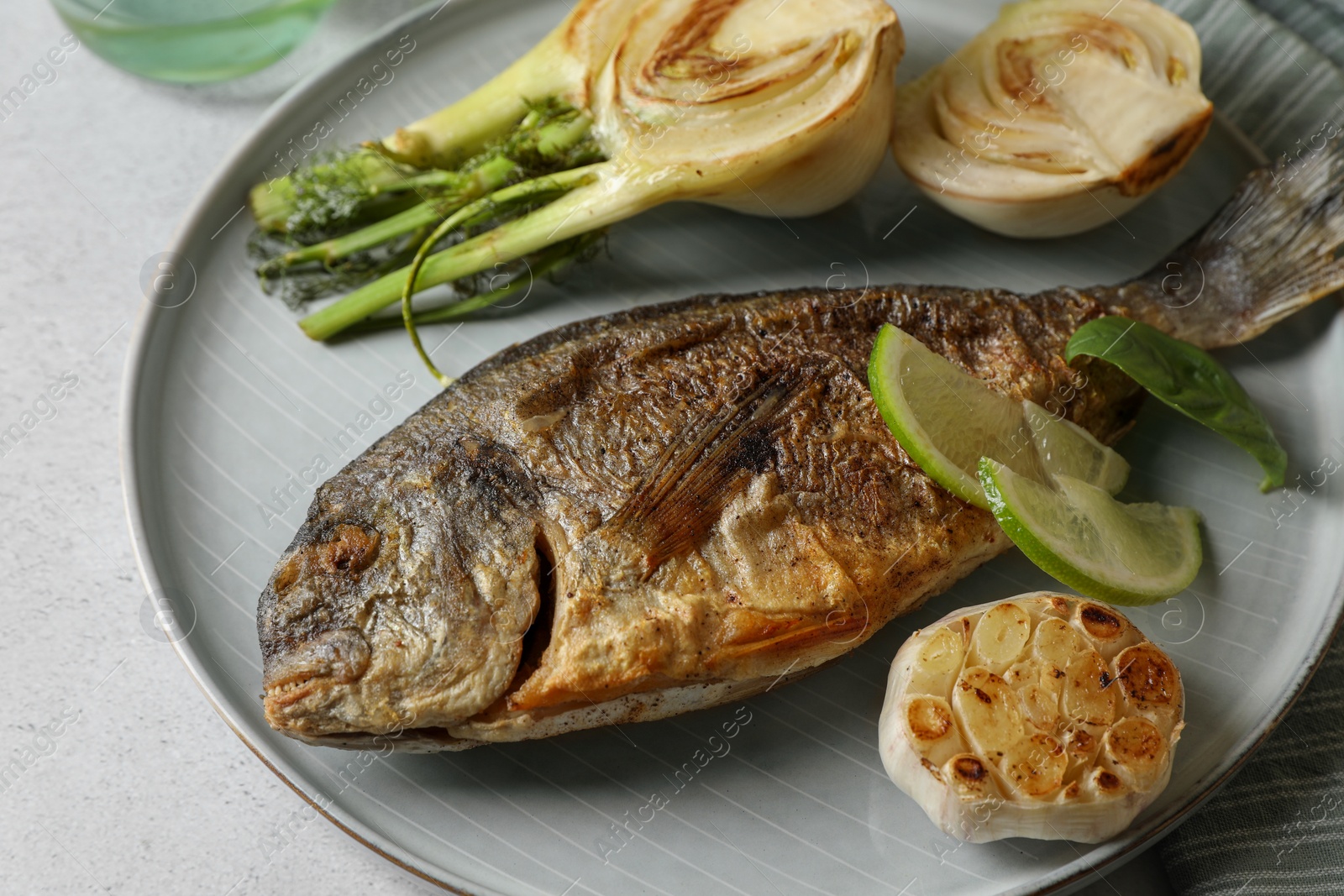 Photo of Delicious dorado fish with vegetables served on table, closeup