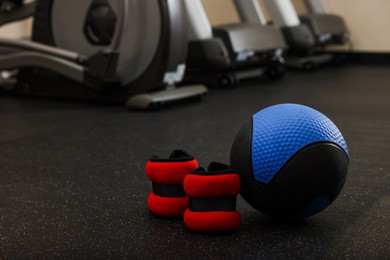 Photo of Blue medicine ball and weighting agents on floor in gym, space for text