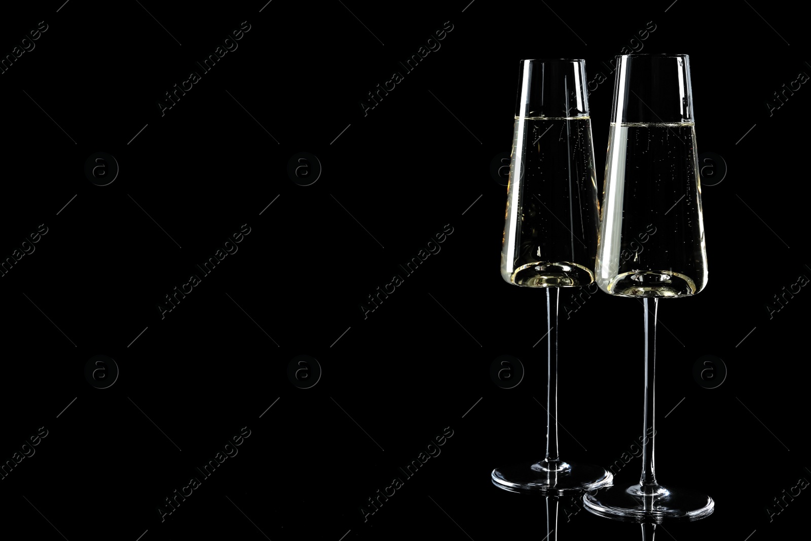 Photo of Glasses of champagne on black background, space for text