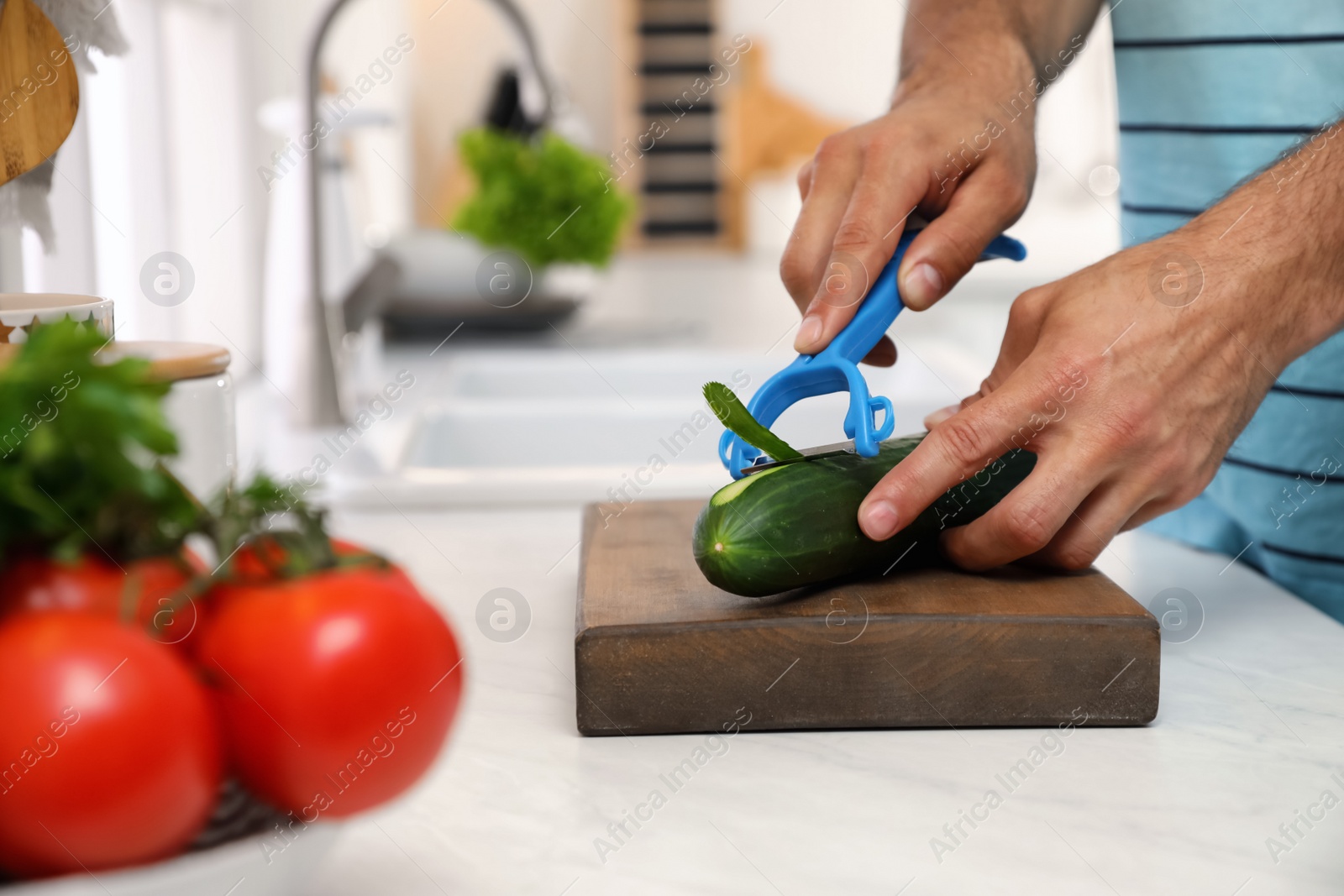 Photo of Man peeling cucumber at kitchen counter. Preparing vegetable