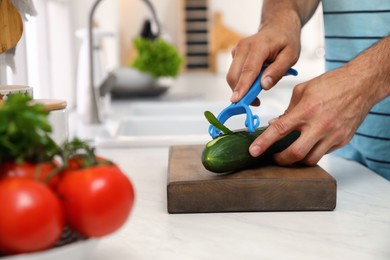 Man peeling cucumber at kitchen counter. Preparing vegetable