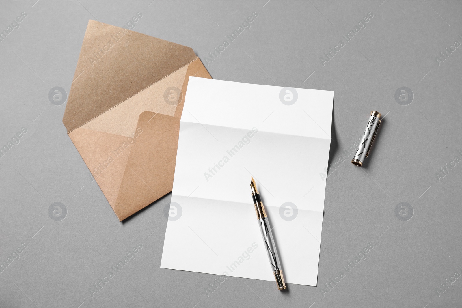 Photo of Blank sheet of paper, letter envelope and pen on grey background, top view