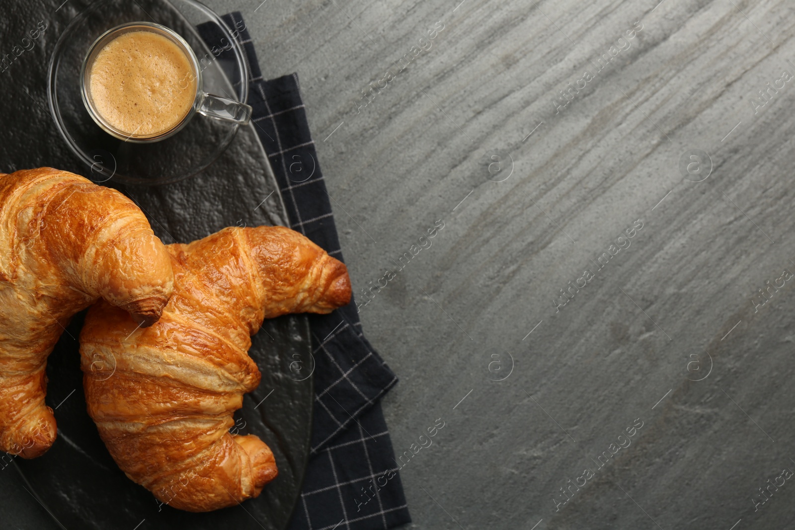 Photo of Delicious fresh croissants and cup of coffee on gray table, flat lay. Space for text