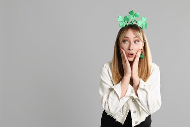 Emotional woman in St Patrick's Day outfit on light grey background, space for text