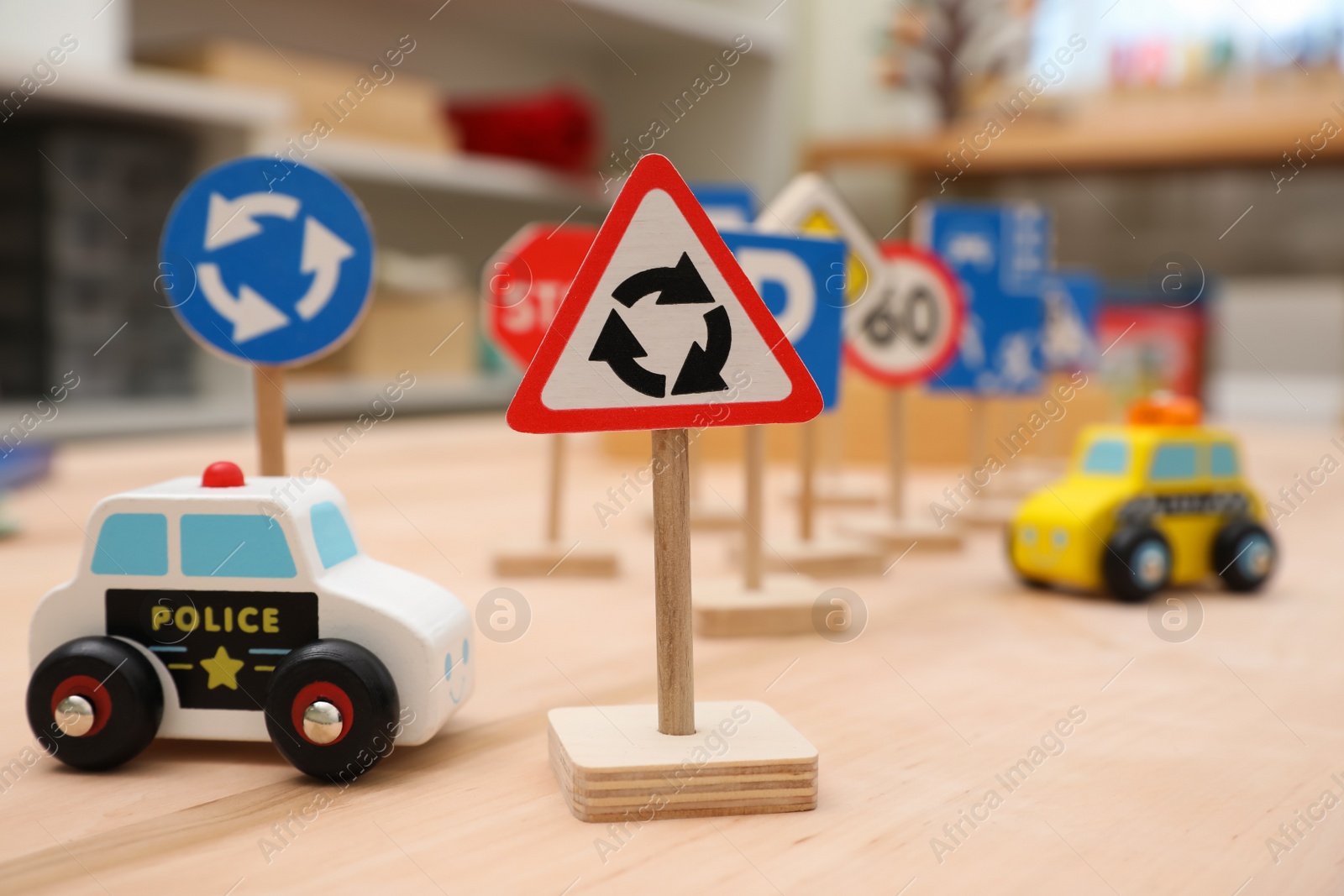 Photo of Different miniature road signs and cars on wooden table. Montessori toy