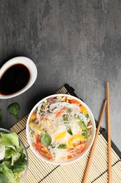 Tasty cooked rice noodles with vegetables served on grey table, flat lay. Space for text