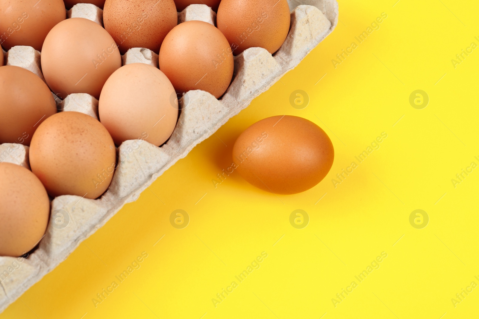 Photo of Raw chicken eggs on yellow background, flat lay