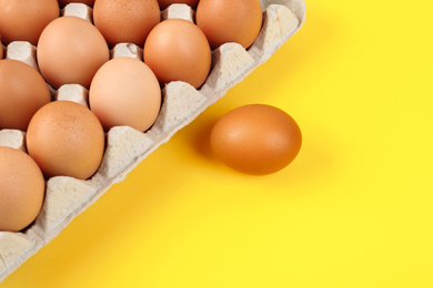 Photo of Raw chicken eggs on yellow background, flat lay