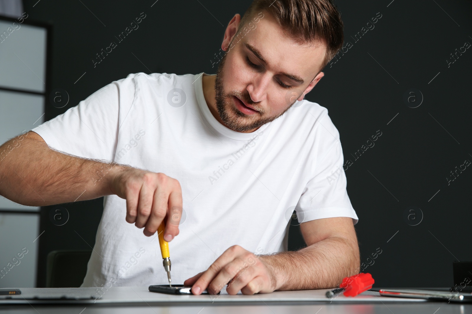 Photo of Technician repairing mobile phone at table in workshop