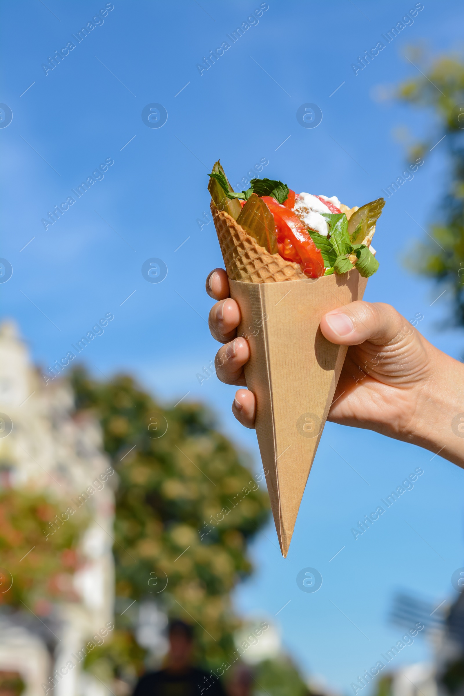 Photo of Woman holding wafer with falafel and vegetables outdoors, closeup. Street food