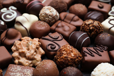 Photo of Different delicious chocolate candies as background, closeup