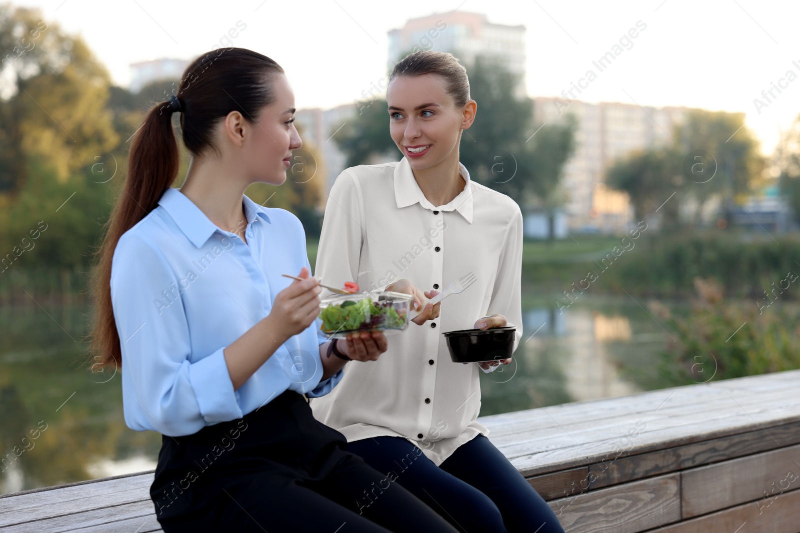 Photo of Smiling business woman talking with her colleague during lunch outdoors