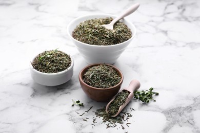 Bowls, scoop and spoon with dried thyme on white marble table