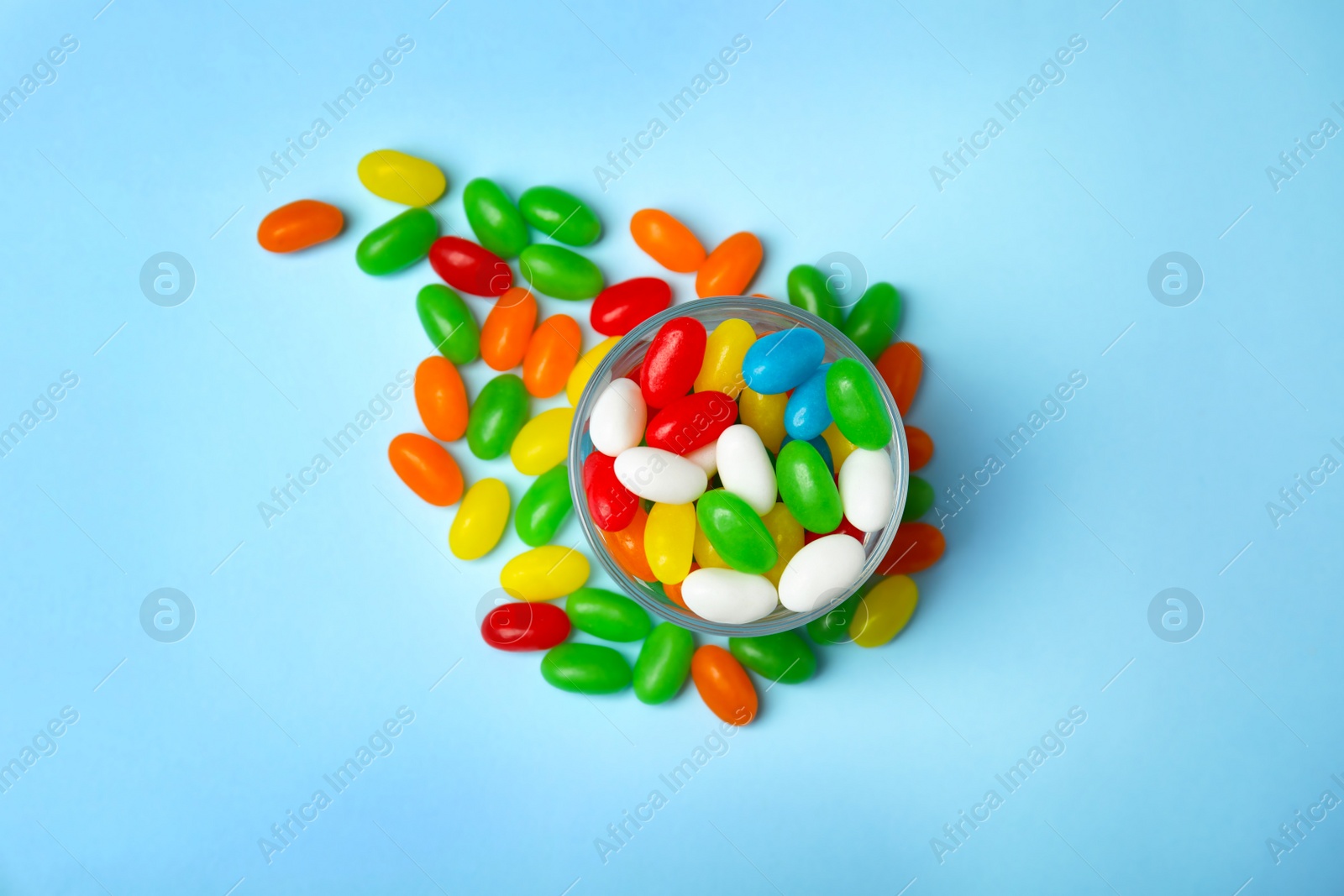 Photo of Flat lay composition with bowl of jelly beans on color background