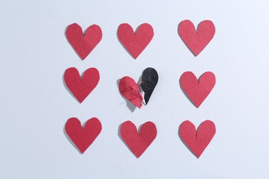 Halves of torn paper heart connected by thread and red decorative hearts on gray background, flat lay. Relationship problem concept