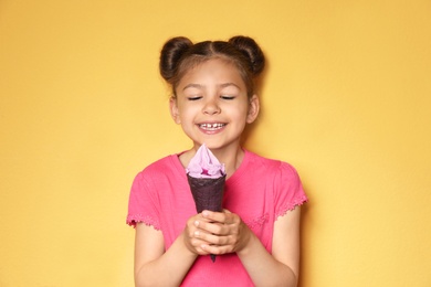 Adorable little girl with delicious ice cream against color background