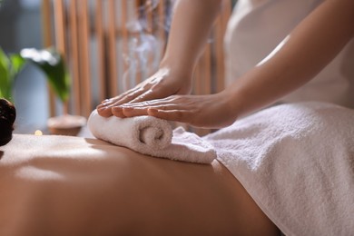 Photo of Spa therapy. Beautiful young woman lying on table during hot towel massage in salon, closeup