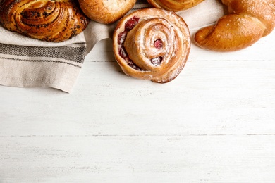 Photo of Different delicious fresh pastries on white wooden background, flat lay. Space for text